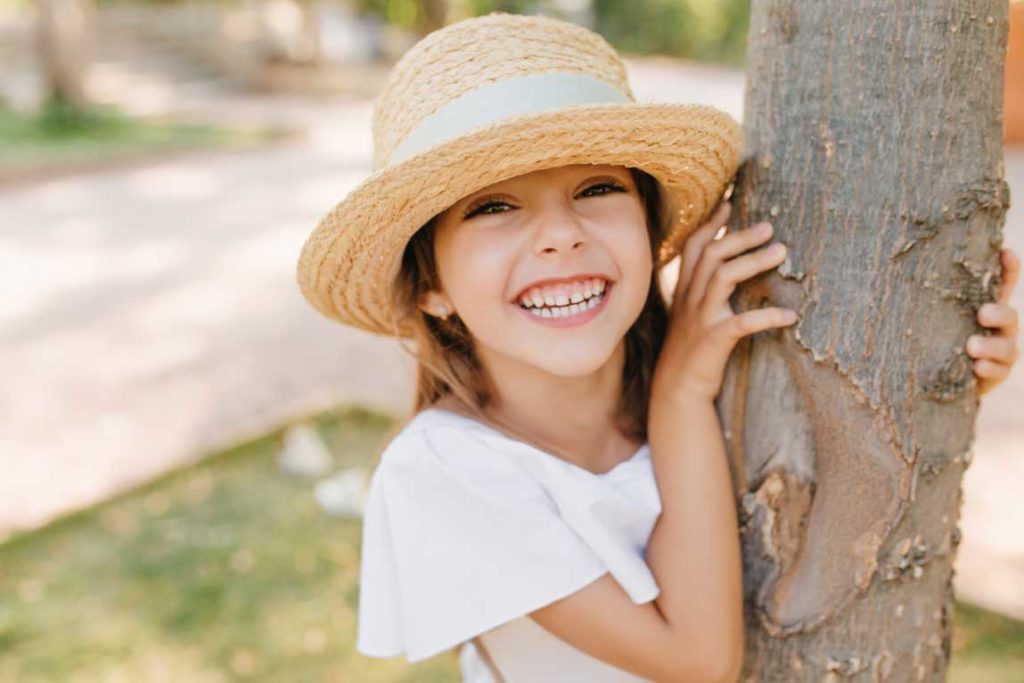 mantenitore di spazio: bambina con cappello che sorride con i suoi dentini da latte